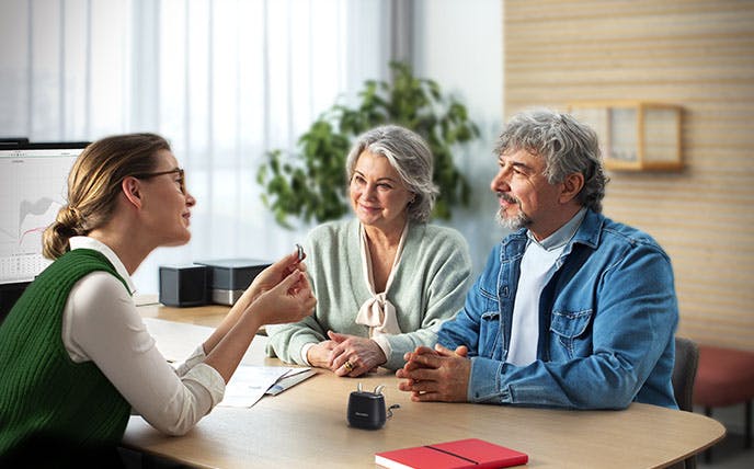 Hearing care professionals engaged in a counselling session with older couple.